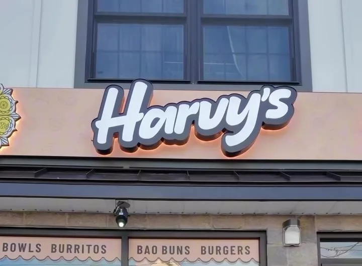 The Harvy's storefront on Easton Avenue: the lit Harvy's sign above a window reading Bowls, Burritos, Bao Buns, Burgers.